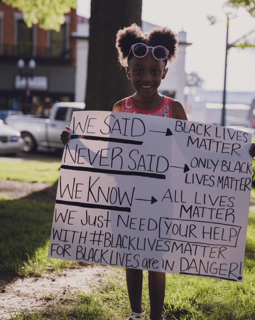 A protestor in Tennessee shows off a sign explaining the meaning of "Black lives matter." Jameela Jamil specifies her gender pronouns on Instagram. An example of how social movements are changing language in 2020.