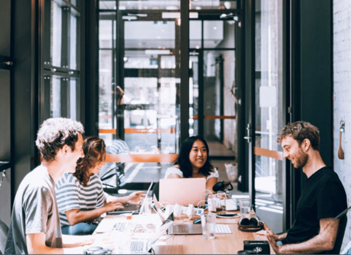 A group of coworkers sitting around a table discussing content marketing tools