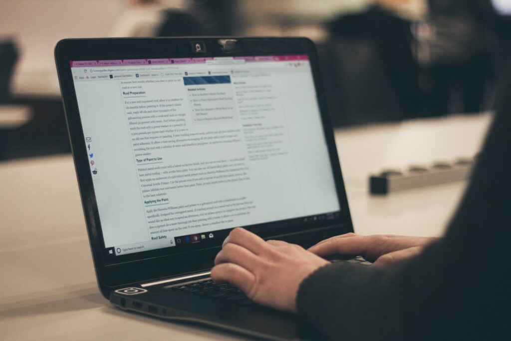 A laptop with persons hands on the keyboard typing content on the screen