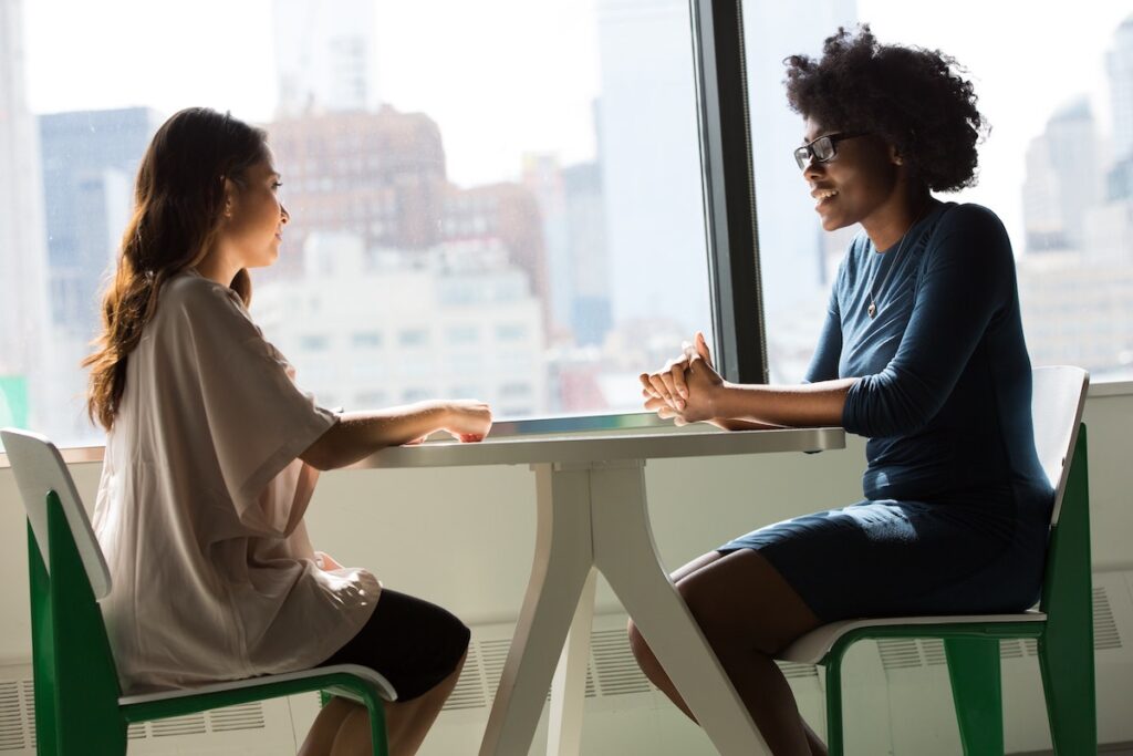 two women having a one-on-one meeting to check in, which is an example of a moment where you can show empathetic leadership