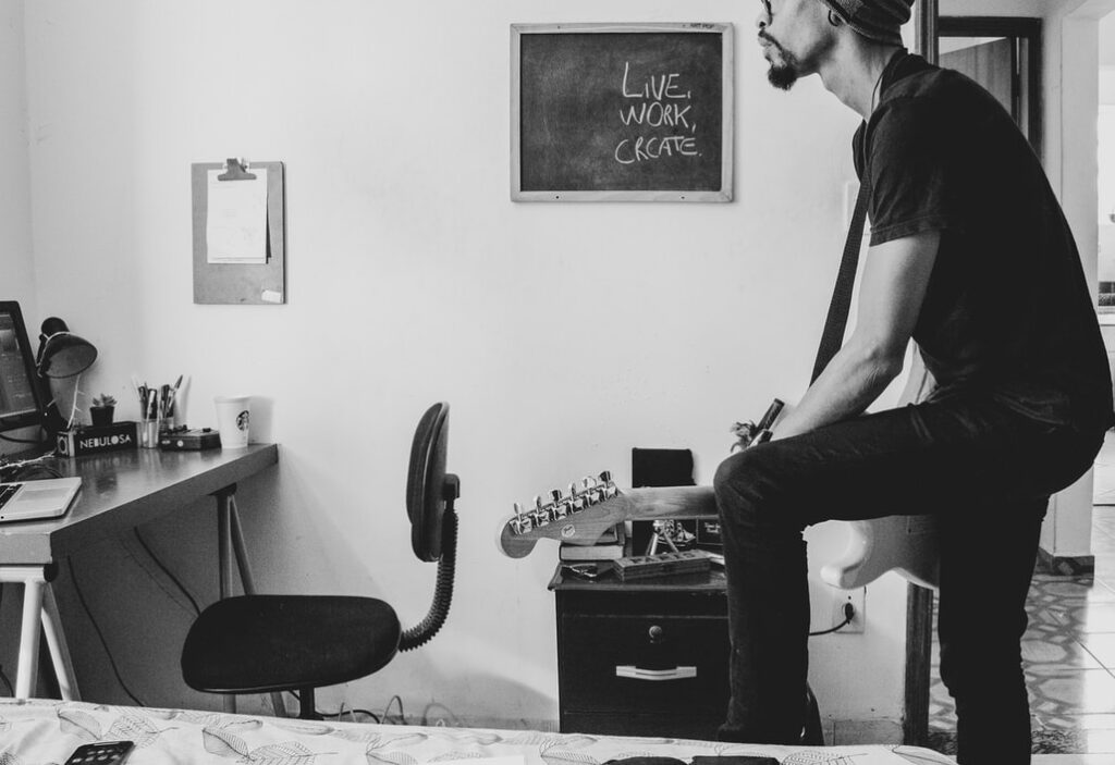 Black-and-white photo of a musician at home playing the guitar