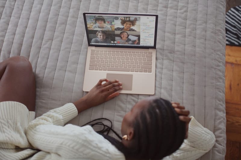 Woman on her bed attending an online event and suffering from zoom fatigue