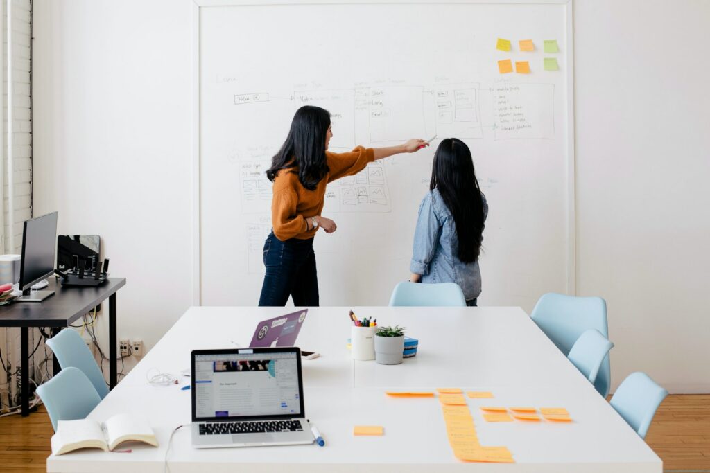 Two coworkers discussing their global marketing localization strategy and pointing to the plans on the wall