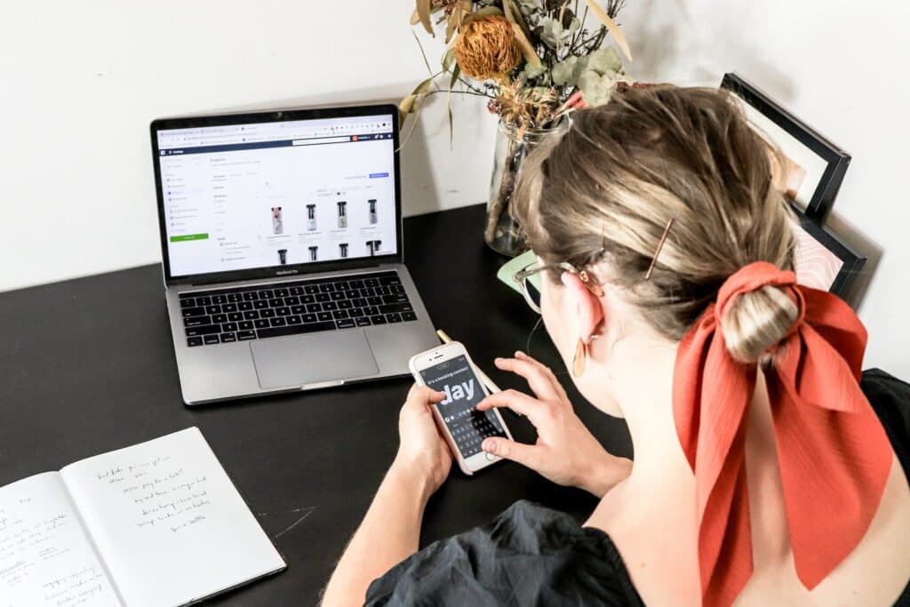 A woman at a social media localization agency who is holding her phone at her desk