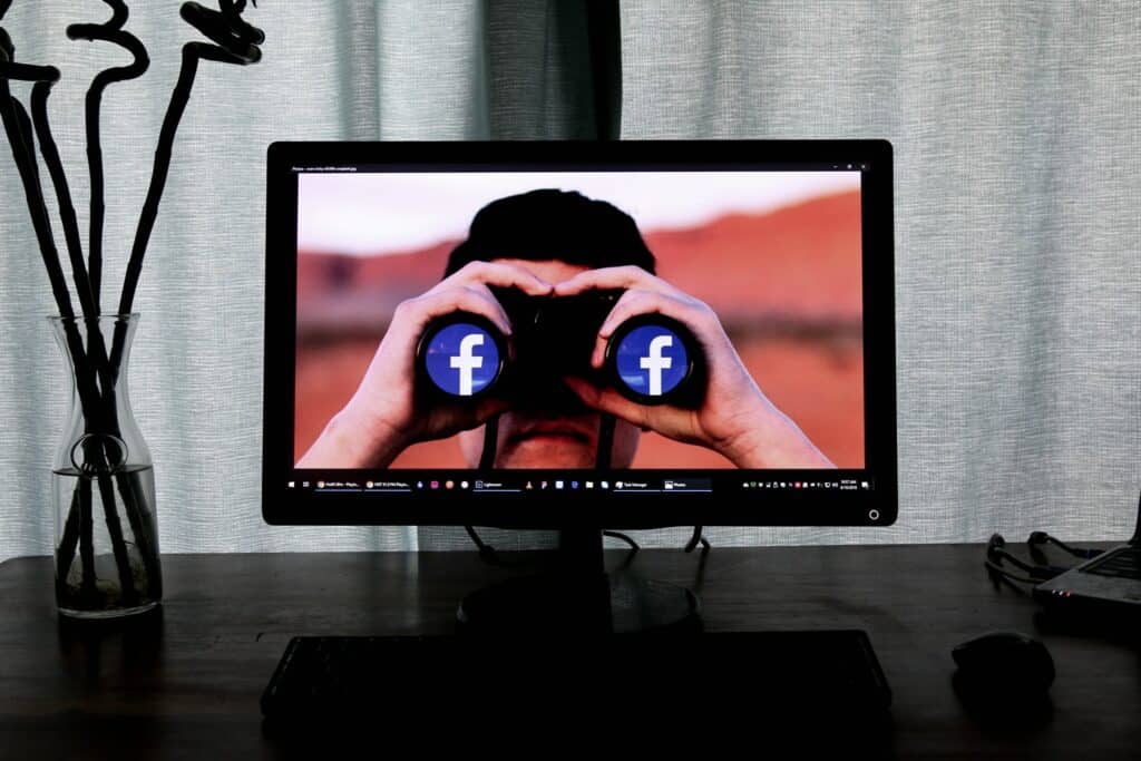 A computer screen showing an image of a person holding binoculars with the Facebook logo