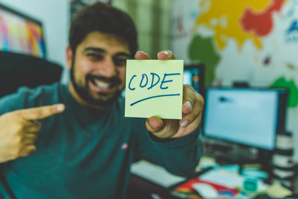 A man holding up a post-it with the word "code"