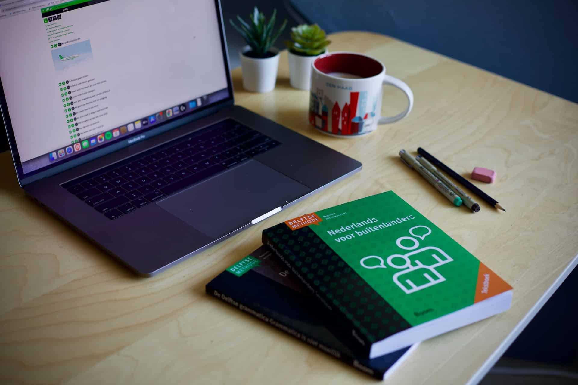 Laptop, books and pens reflecting multilingual copywriting
