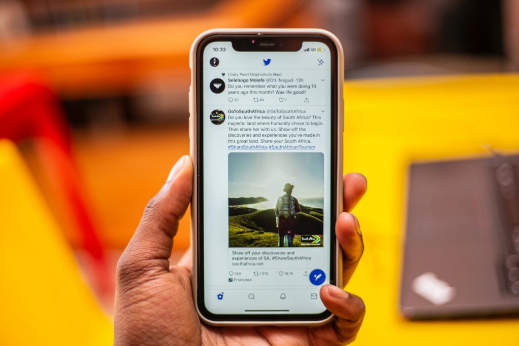 A person holding a phone featuring various posts on Twitter used on an article about multilingual social media management