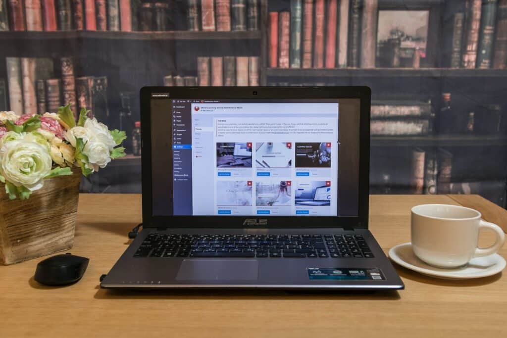 A laptop showing the backend of a multilingual content management system with book shelves in the background