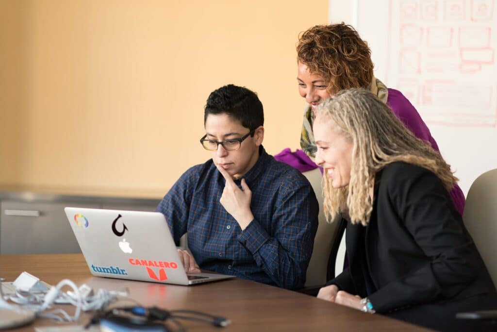 Three employees looking at a computer discussing their multilingual content production