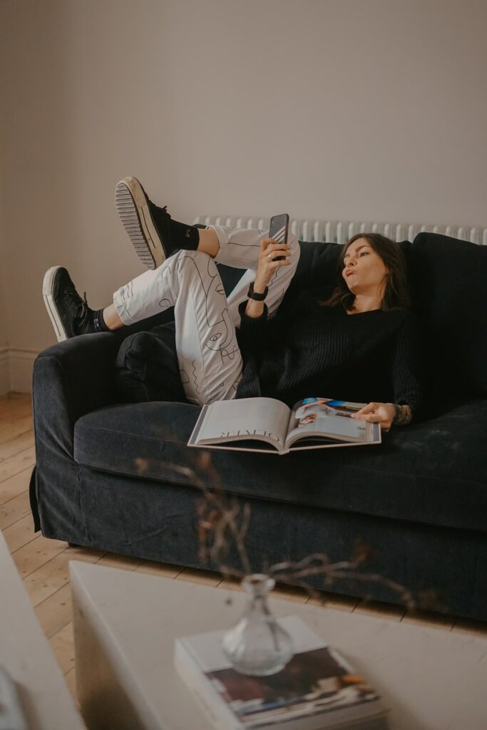 Person on a sofa reading a book at looking at her phone