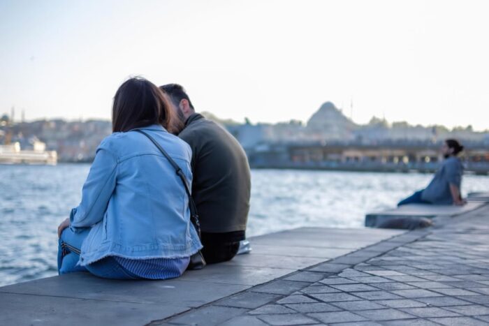 A couple sitting on the shore of the istanbul navial port and enjoying the view