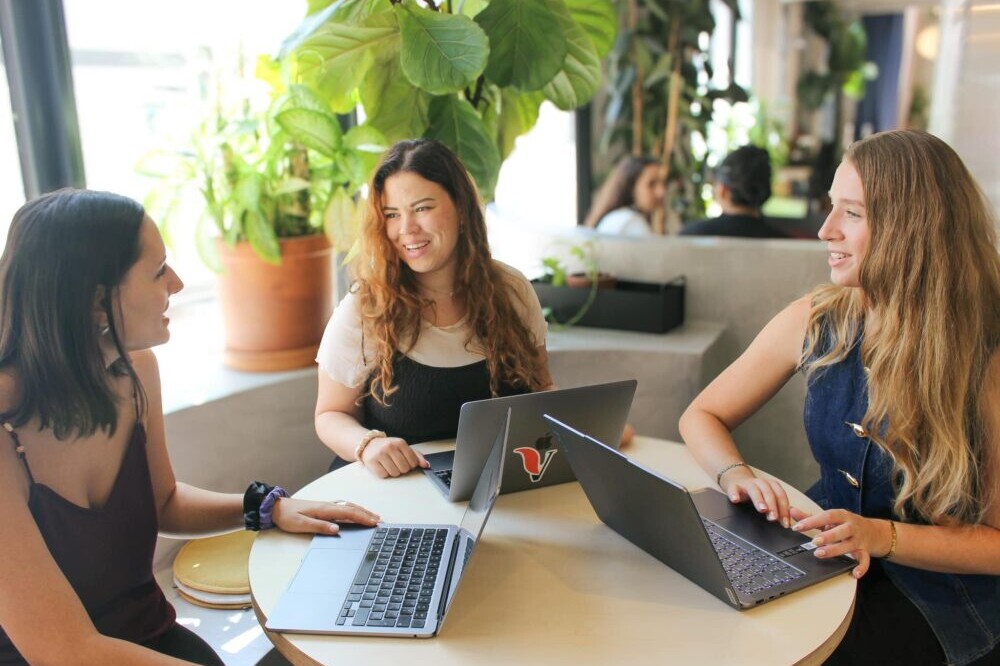 VeraContent team members sitting around a table with their laptops