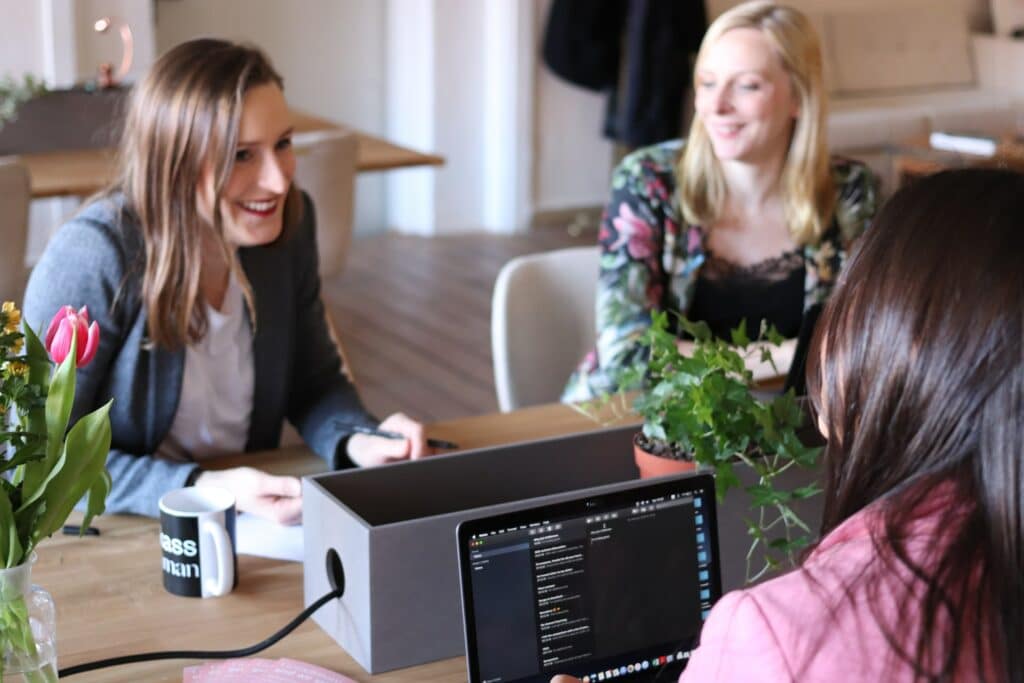 Three people sitting at a desk with laptops, illustrating an audit of multilingual digital presence