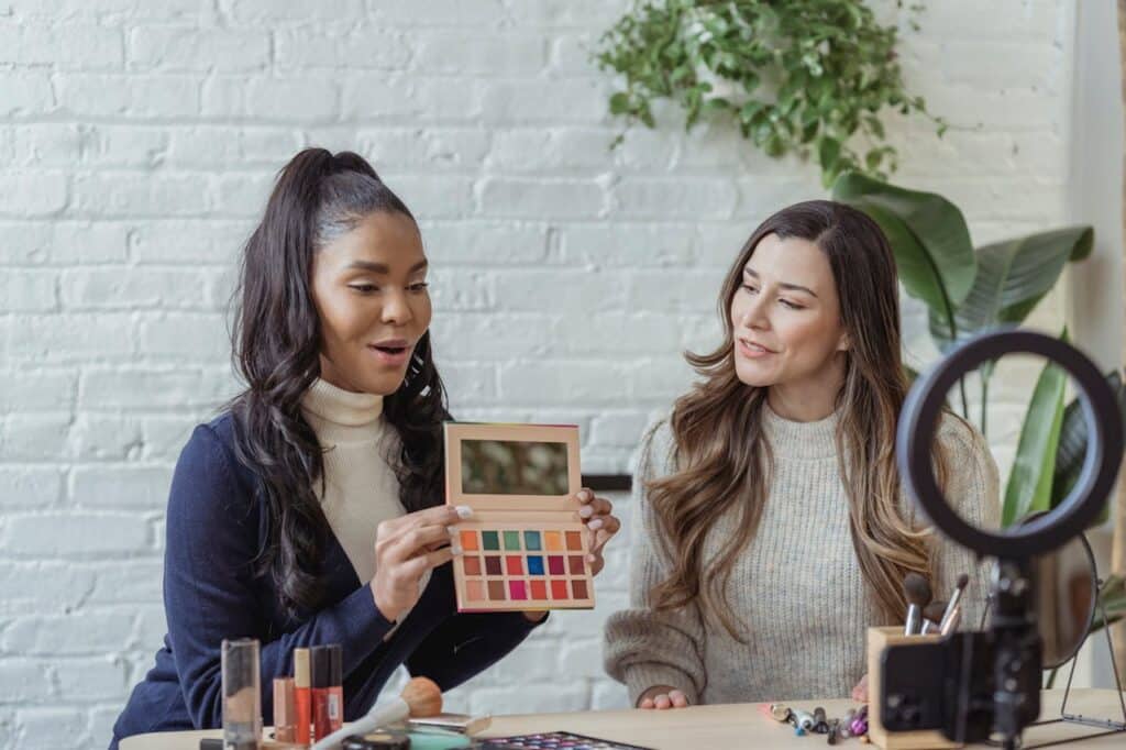 Two content creators filming themselves while showcasing makeup products for user-generated content