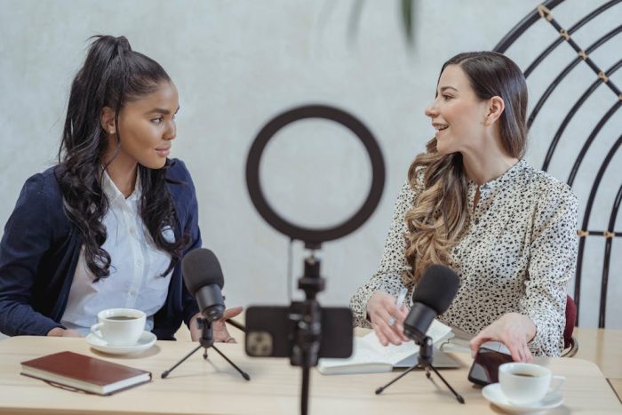 Smiling woman interviewing female guest and recording video
