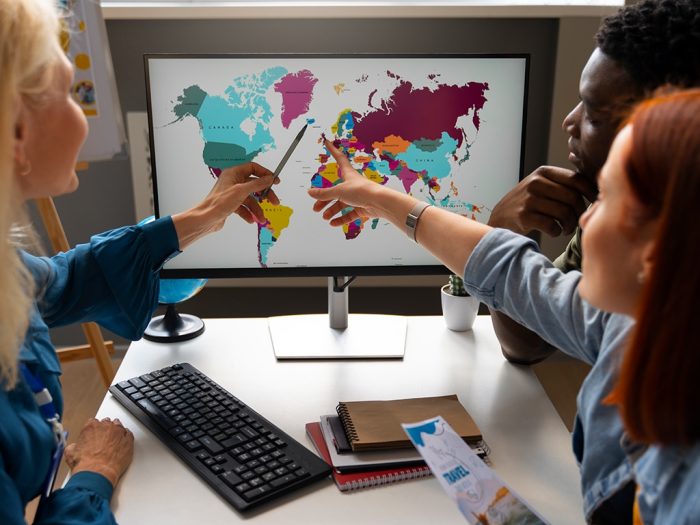 coworkers pointing to world map while discussing local marketing for global brands